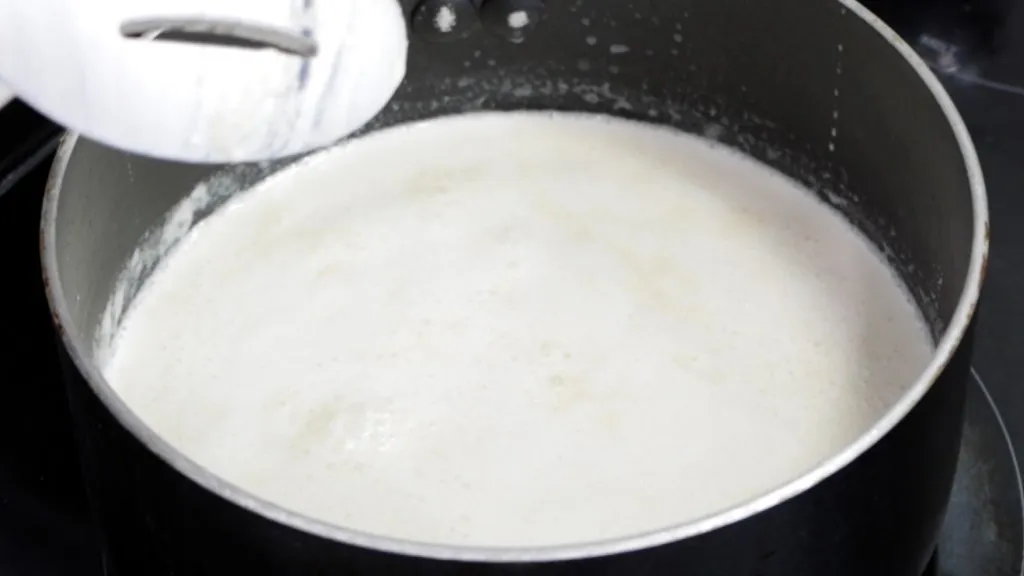 Pot of hot cream and milk on a stovetop burner