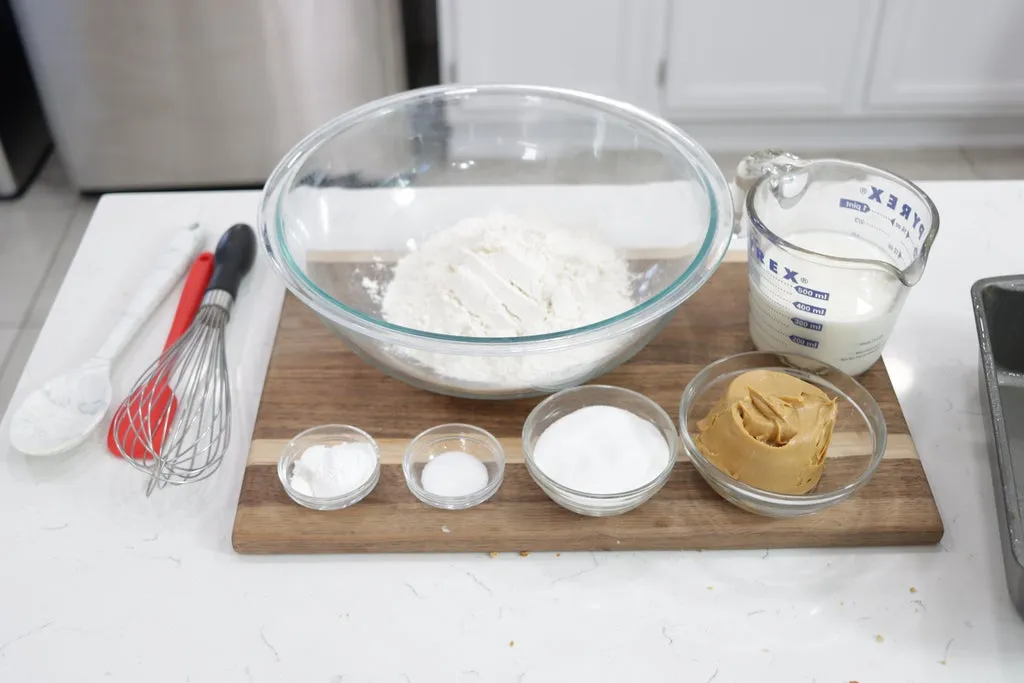 Several ingredients in glass bowls on top of a wooden cutting board.