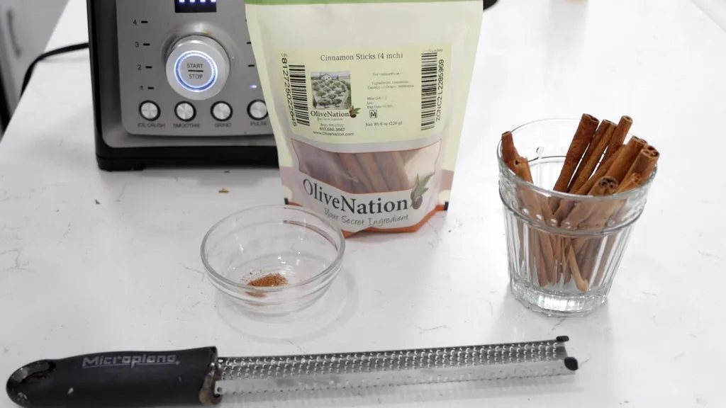 Microplane zester and cinnamon sticks and blender on a counter.
