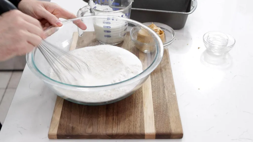 Hand whisking dry ingredients in a large bowl.