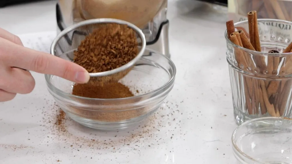 Hand sifting cinnamon chunks form cinnamon powder.