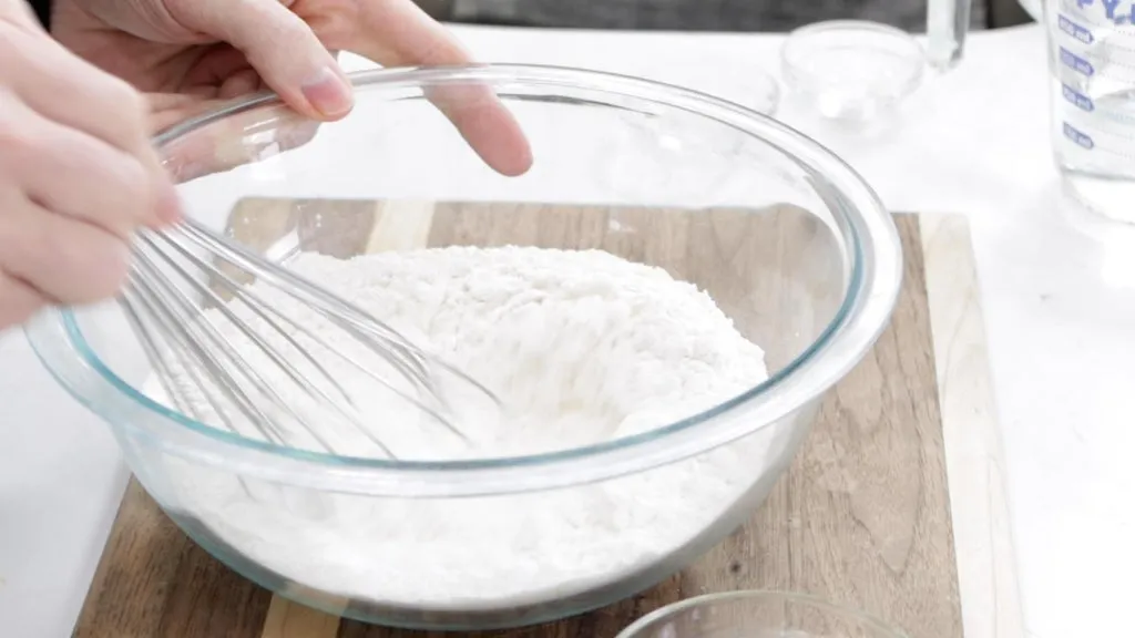 Hand whisking flour with salt and baking powder.