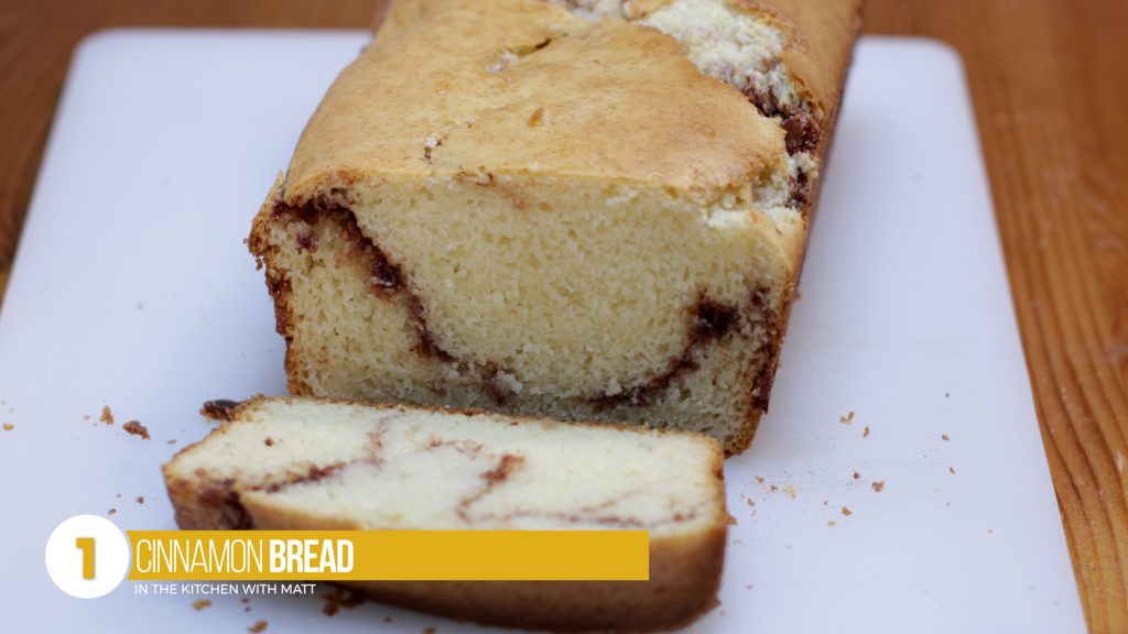 Loaf of cinnamon quick bread on a white cutting board.