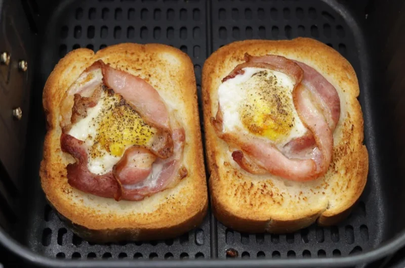 bacon and egg toast resting in the air fryer basket.