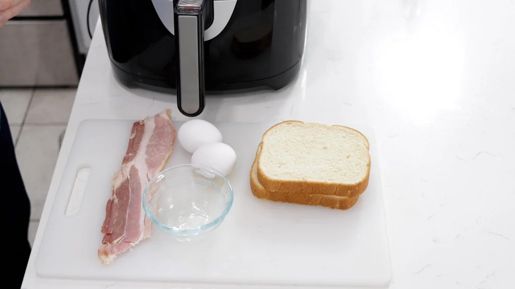 Bacon, eggs, bread, and an air fryer on a counter.