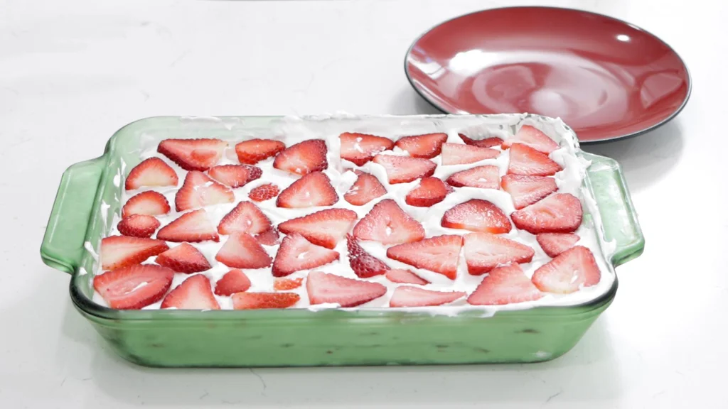 Finished strawberry icebox cake in a green glass dish on top of a white counter.