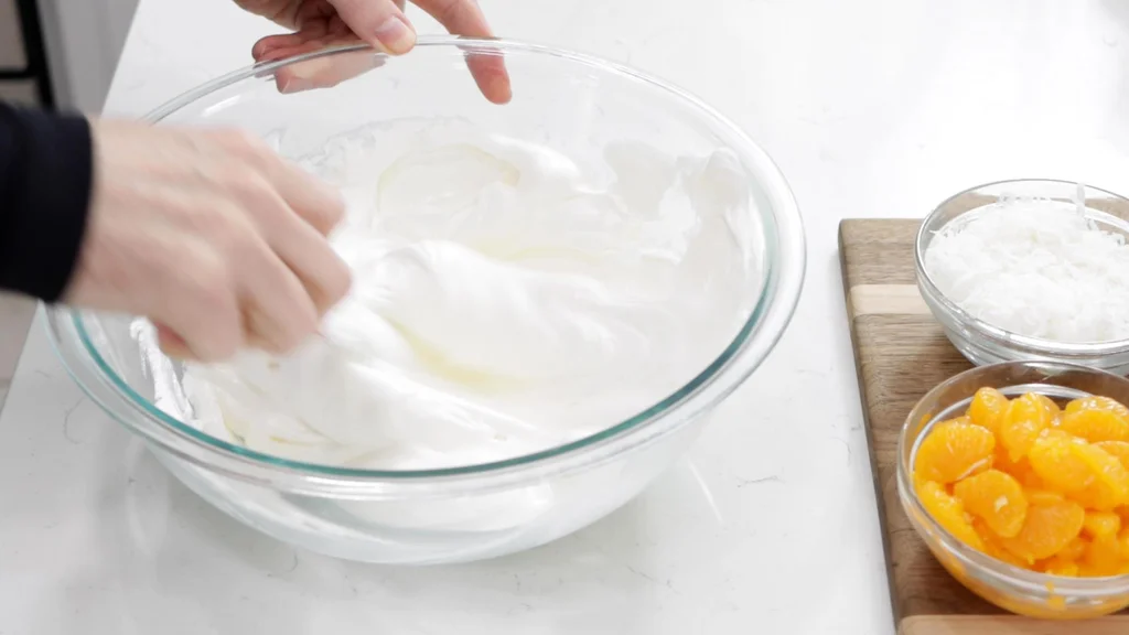 Hand mixing together sour cream and whipped topping in a large bowl