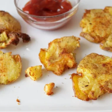 air fryer smashed potatoes on a plate with a bowl of ketchup