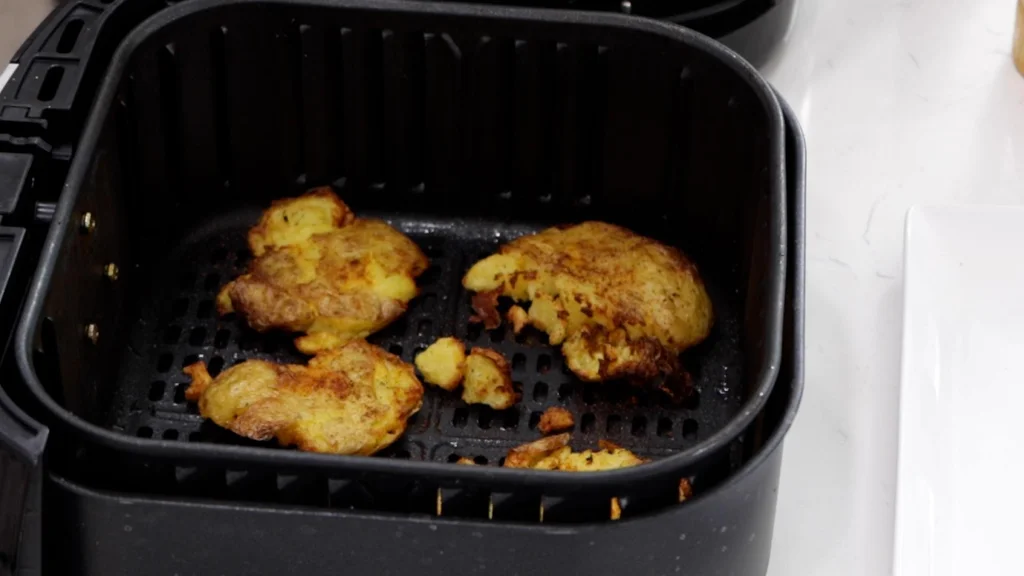Finished smashed potatoes in air fryer basket.