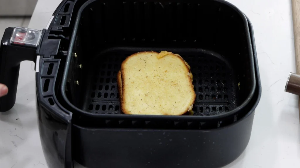 Almost completely cooked grilled cheese sandwich in an air fryer basket.