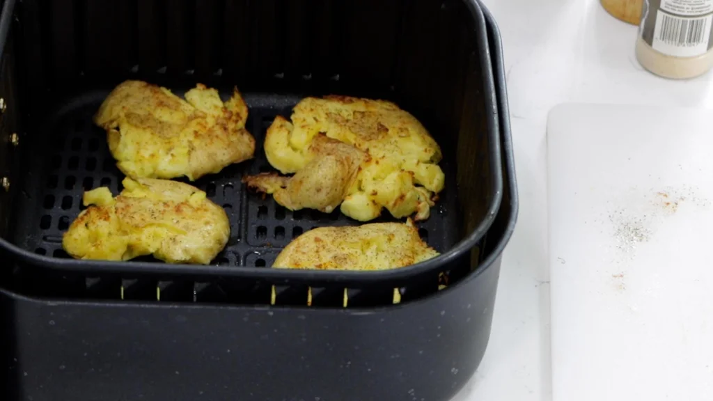 Smashed potatoes in an air fryer basket.