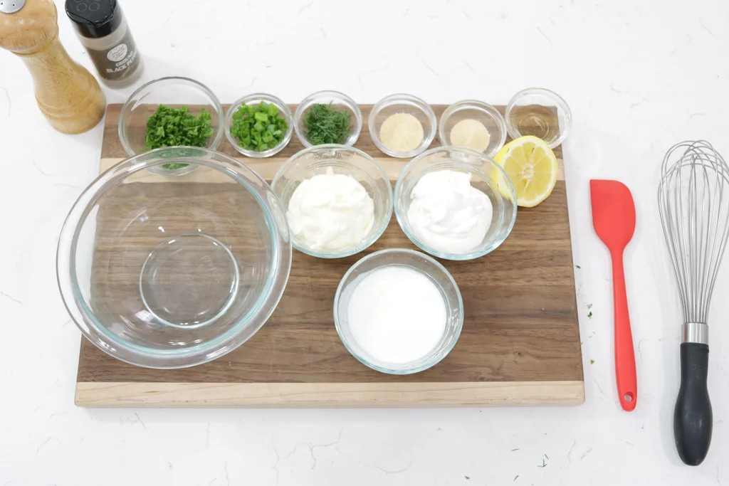 Several ingredients in glass bowls on a wooden cutting board.