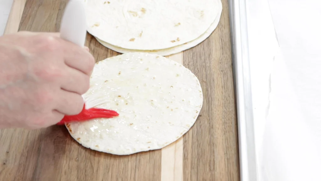 Hand basting butter on a flour tortilla