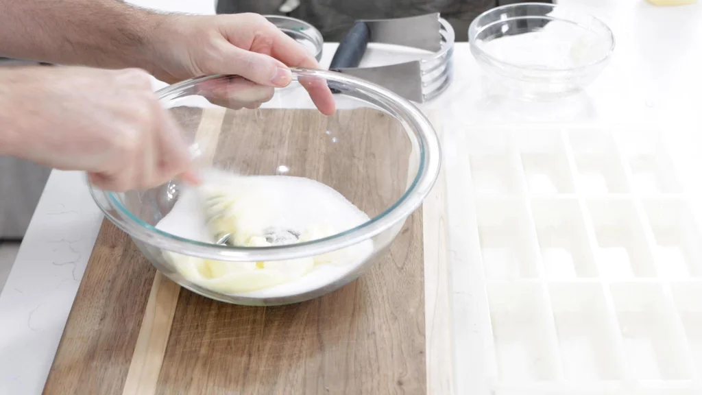 Hand blending sugar and butter together with a fork in a bowl.