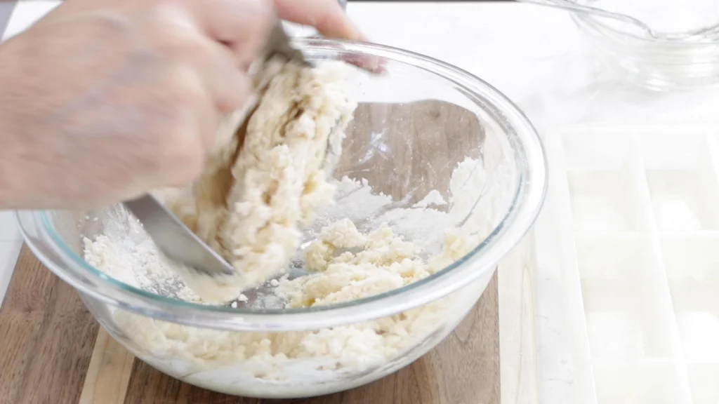 Hand mixing shortbread cookies dough in a large bowl.