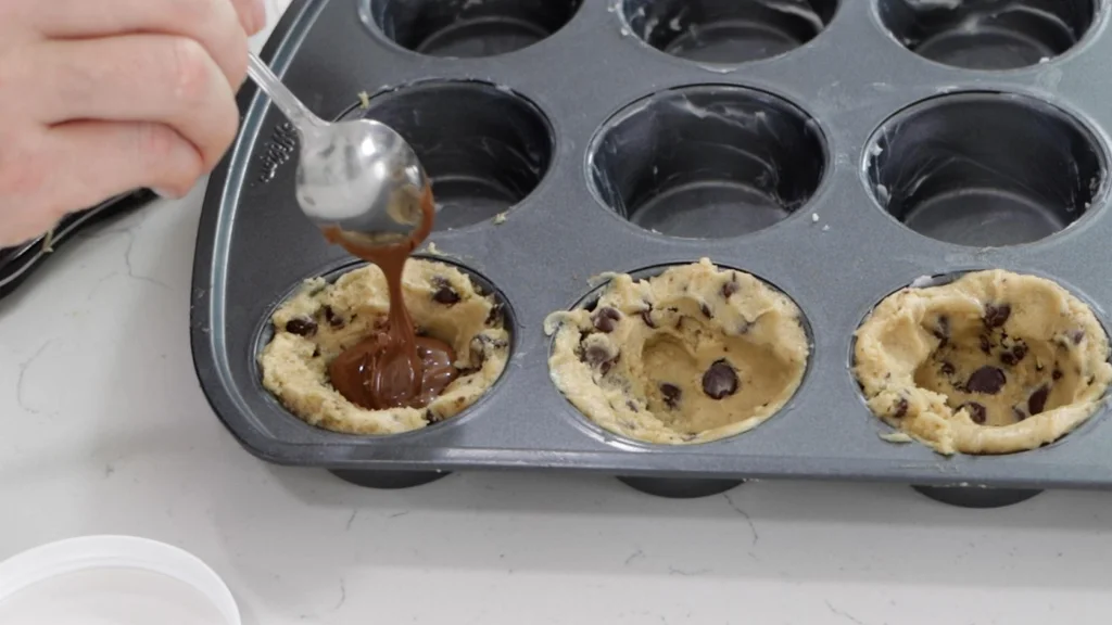 Spoon placing Nutella into a cookie cup