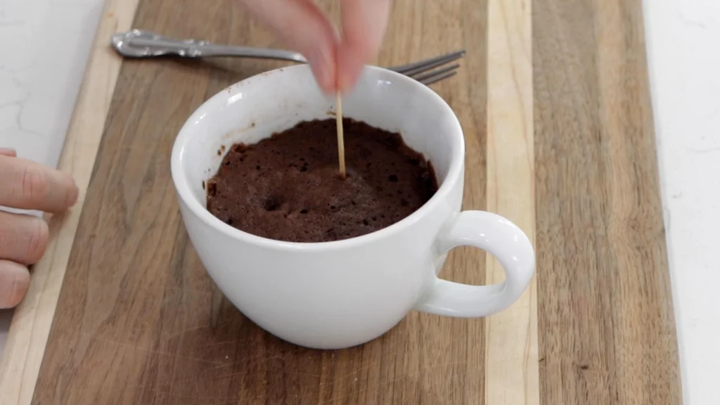 Toothpick checking doneness of a chocolate mug cake.