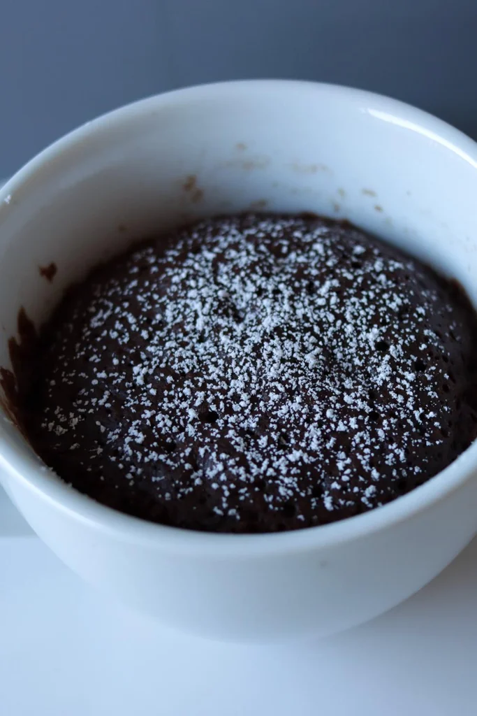 Chocolate mug cake in a white bowl on a white plate.