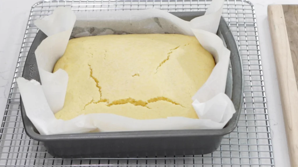 Freshly baked cornbread in pan on wire rack.