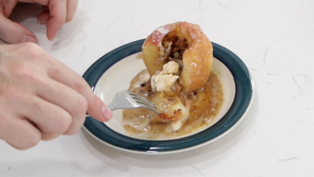 Hand cutting into a baked apple.