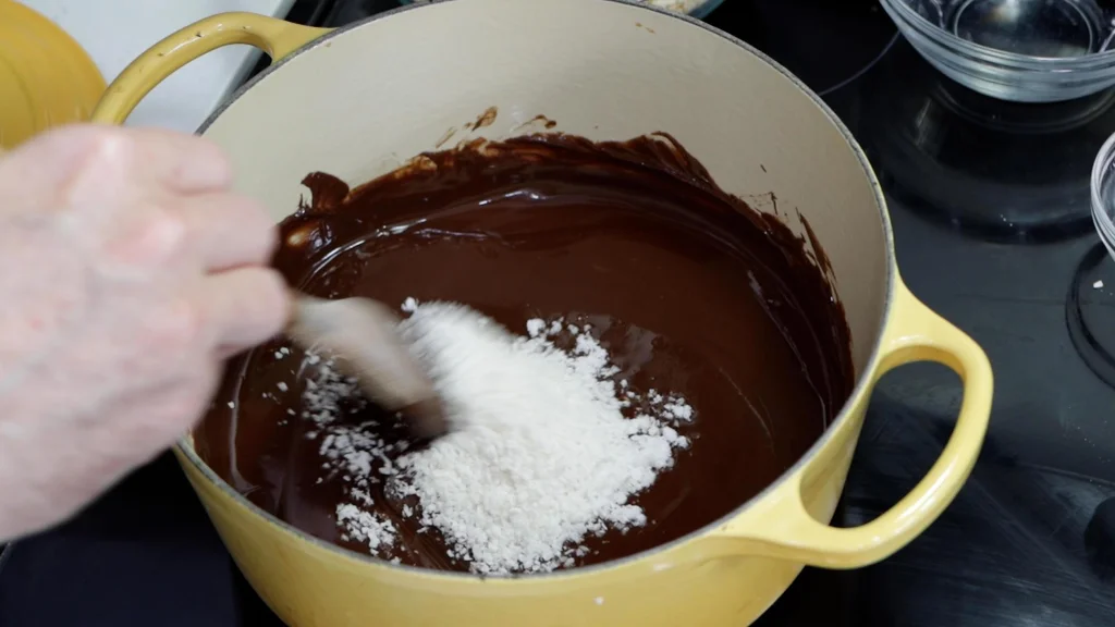 Coconut in a pot of melted chocolate.