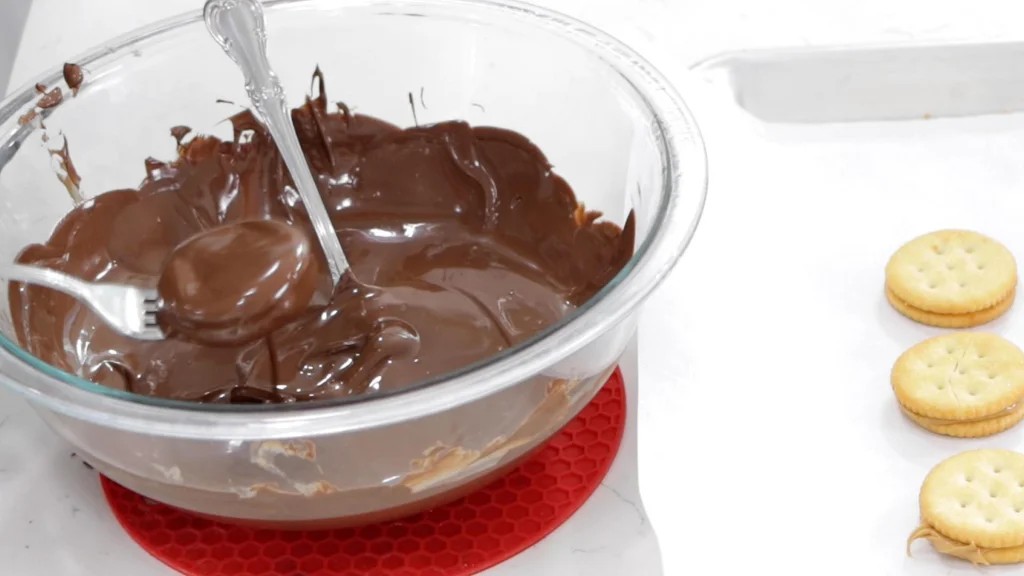Ritz peanut butter crackers being dipped in chocolate.
