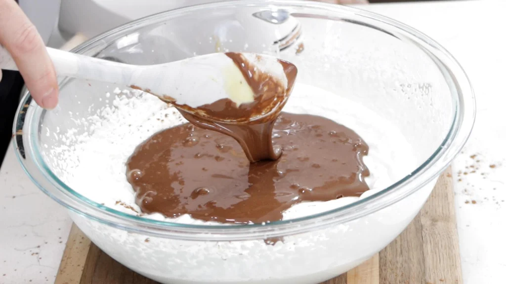 Chocolate sweetened condensed milk with whipped cream in a large bowl.