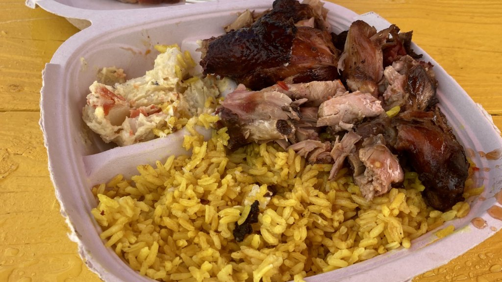 Plate of jerk chicken, yellow rice, and potato salad.
