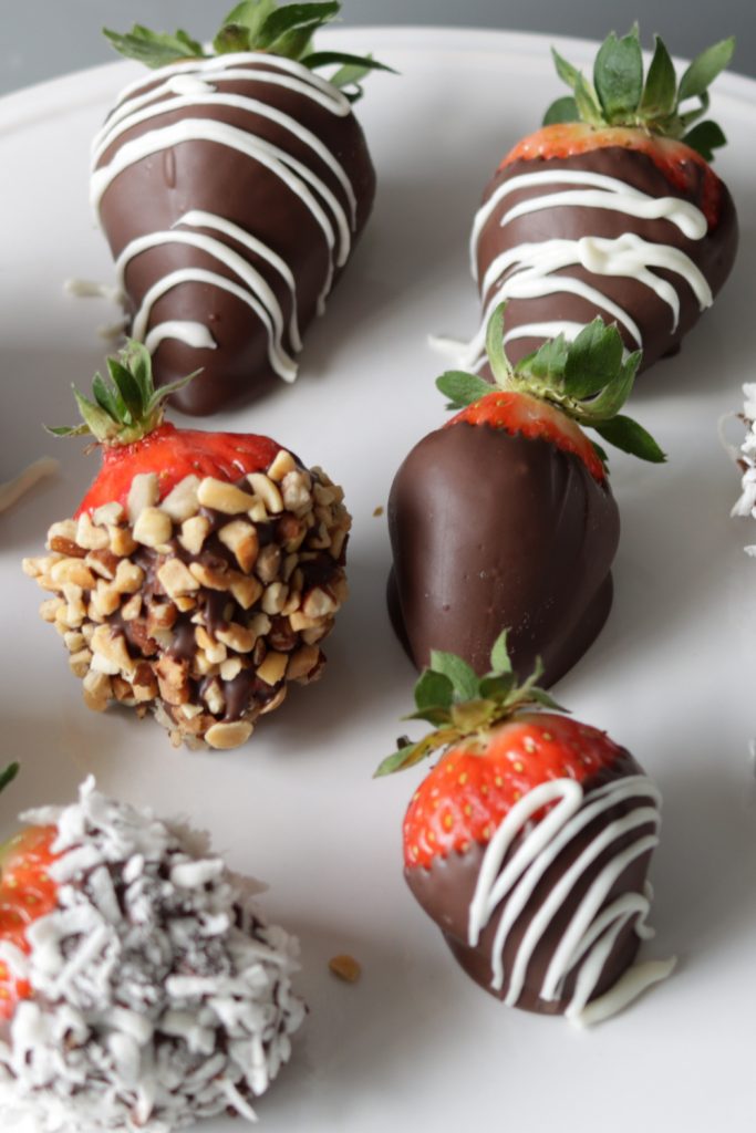Several chocolate covered strawberries on a white plate.