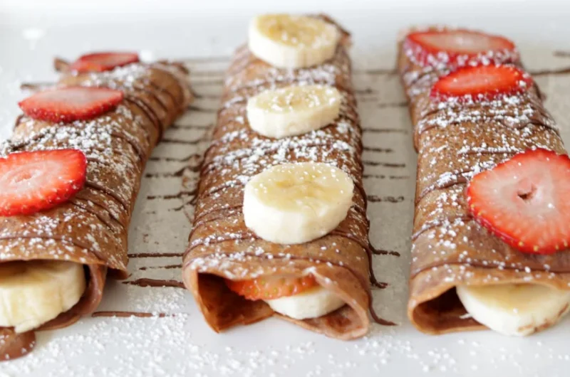 Three Nutella crepes on a white plate.
