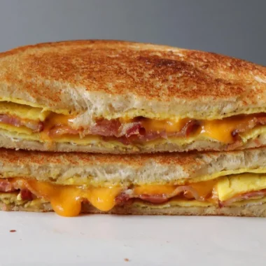 Bacon egg and cheese sandwich on top of a white plate.