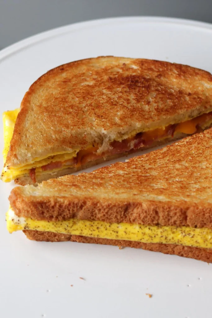Bacon egg and cheese sandwich on a white plate.