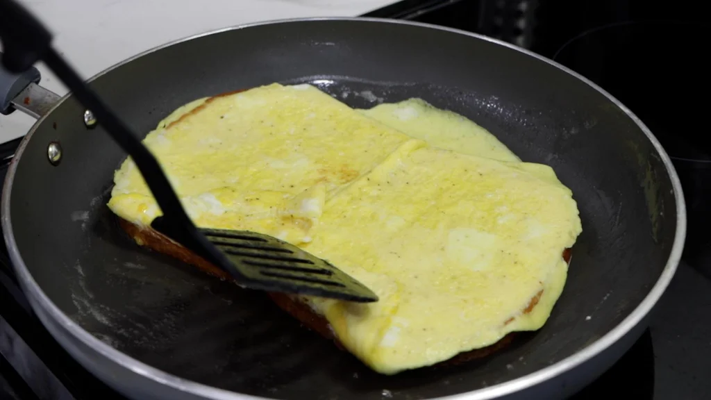 Flipped egg and bread in a skillet.