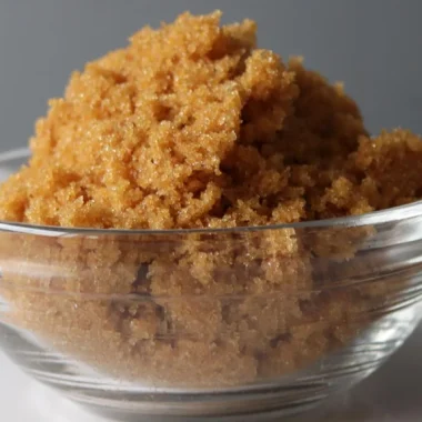 Pile of homemade brown sugar in a glass bowl on a white plate.