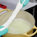 hands stretching homemade mozzarella cheese made from cheap milk