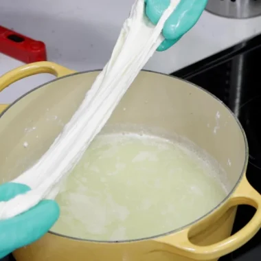 hands stretching homemade mozzarella cheese made from cheap milk
