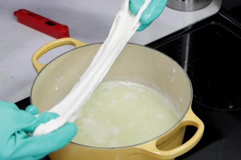 hands stretching homemade mozzarella cheese made from cheap milk