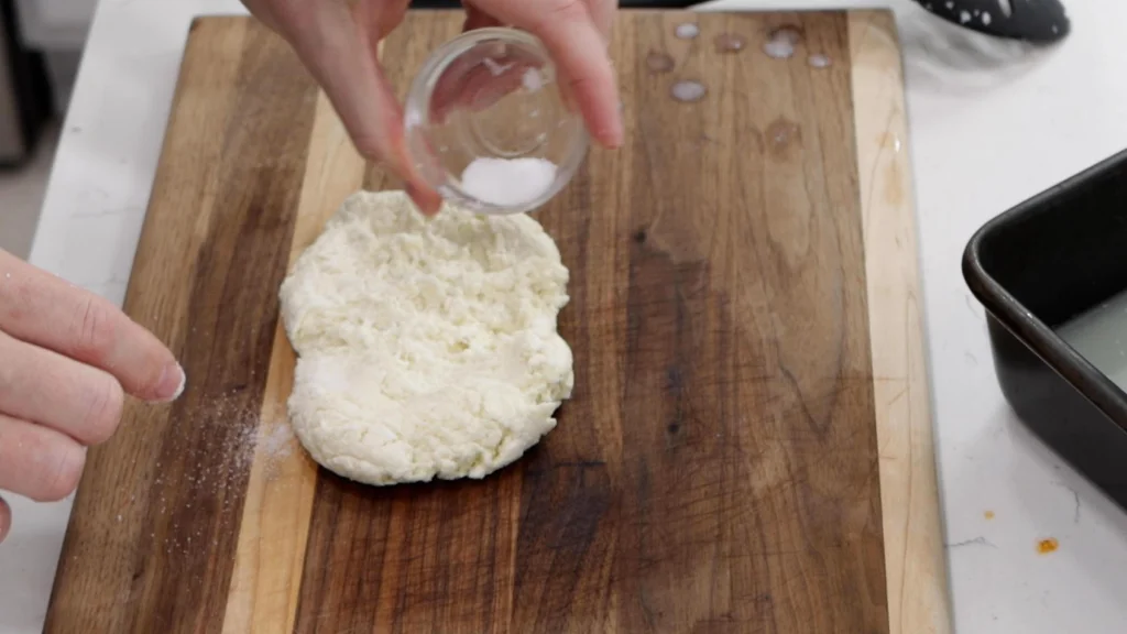 Cheese salt being placed on the ball of mozzarella cheese curd.