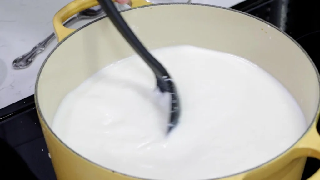 Stirring warm milk with a black slotted spoon