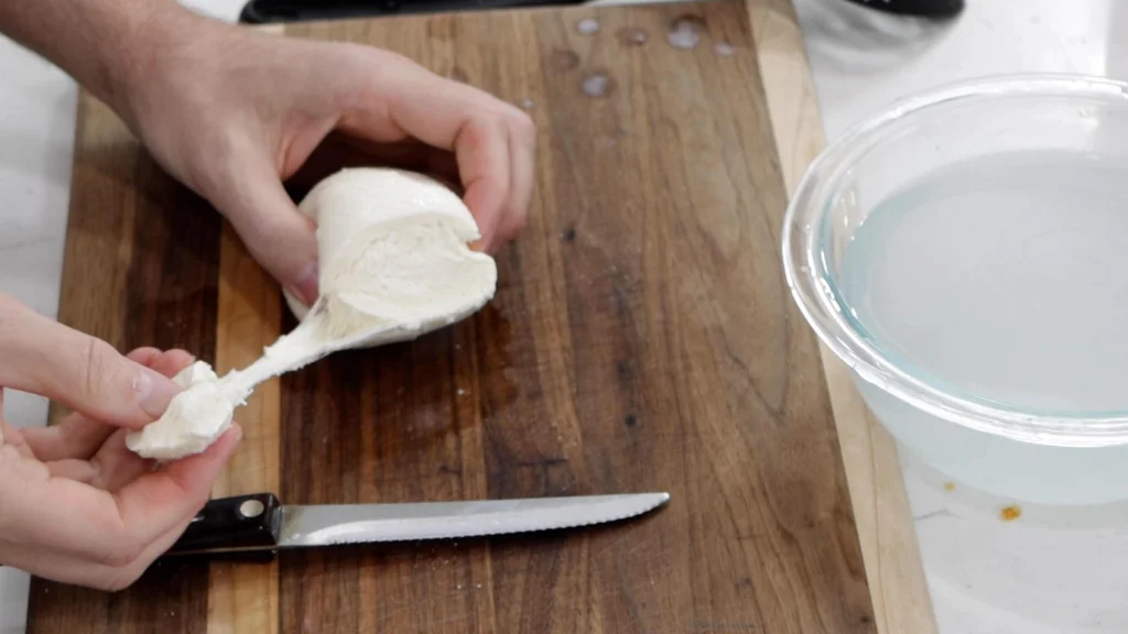 Eating homemade mozzarella cheese off a wooden cutting board.