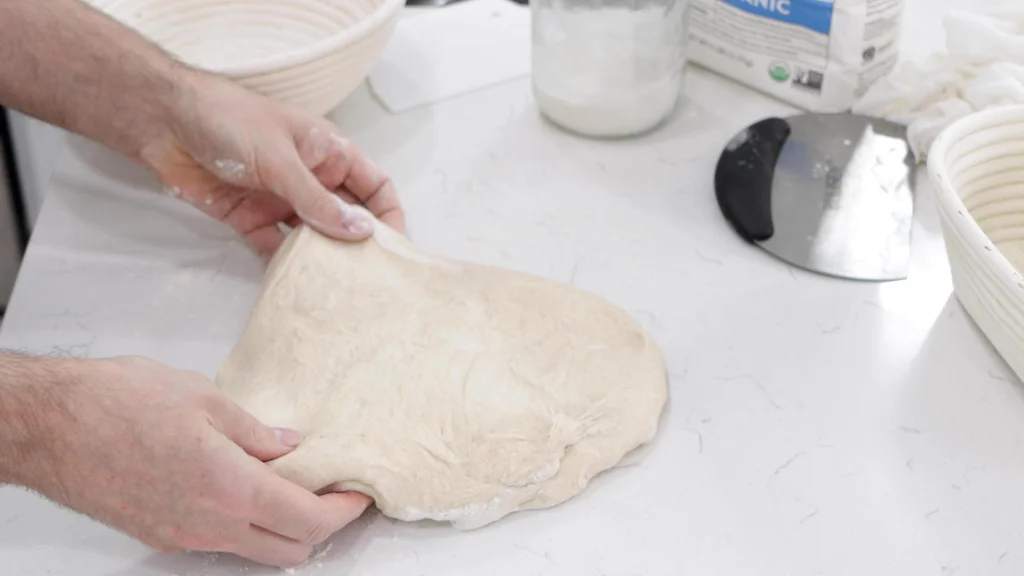 Dough on the counter being stretched into a rectangle.