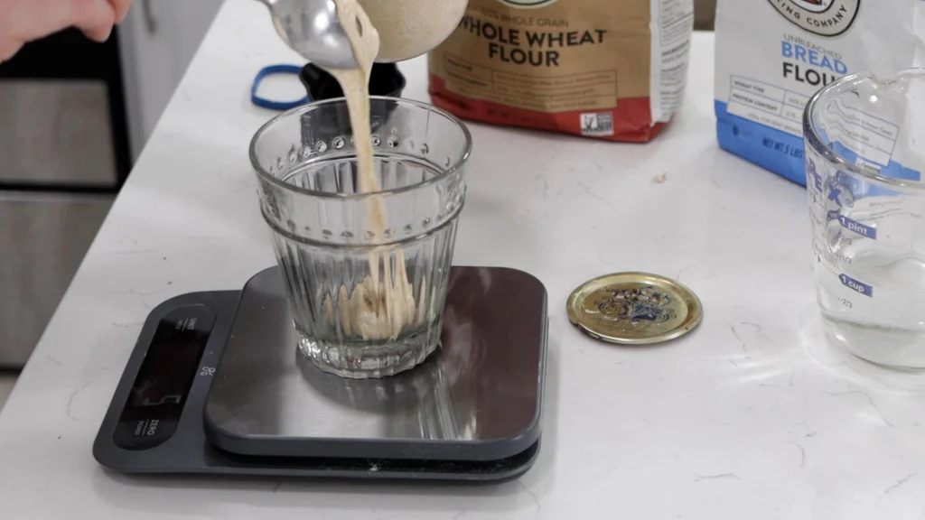 Sourdough starter being placed in a glass on a scale.