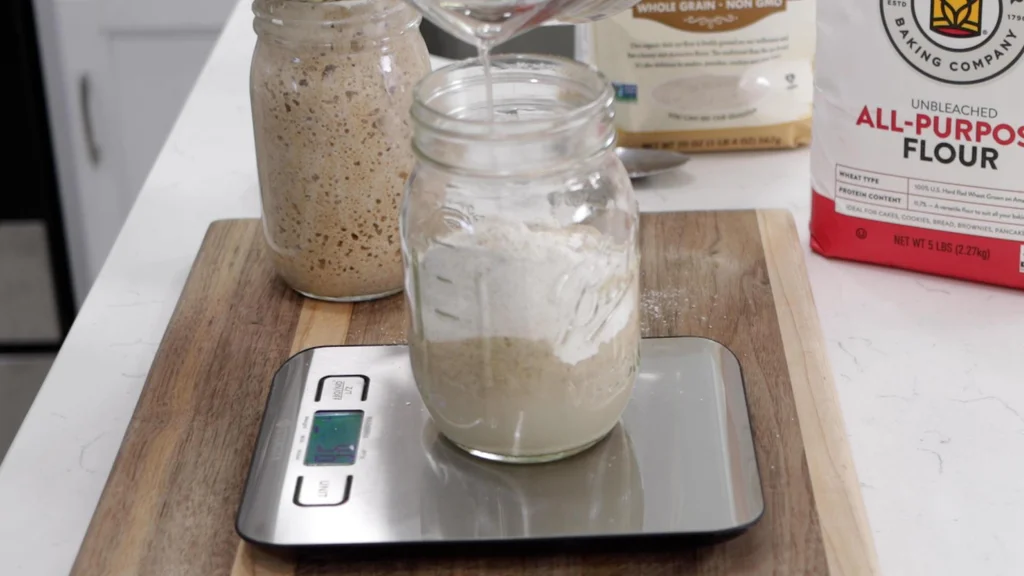 Pouring water into the jar of starter