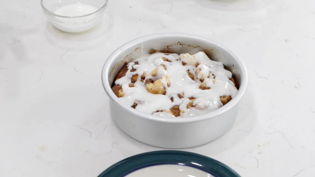 Finished cinnamon rolls in a round cake pan on a counter.