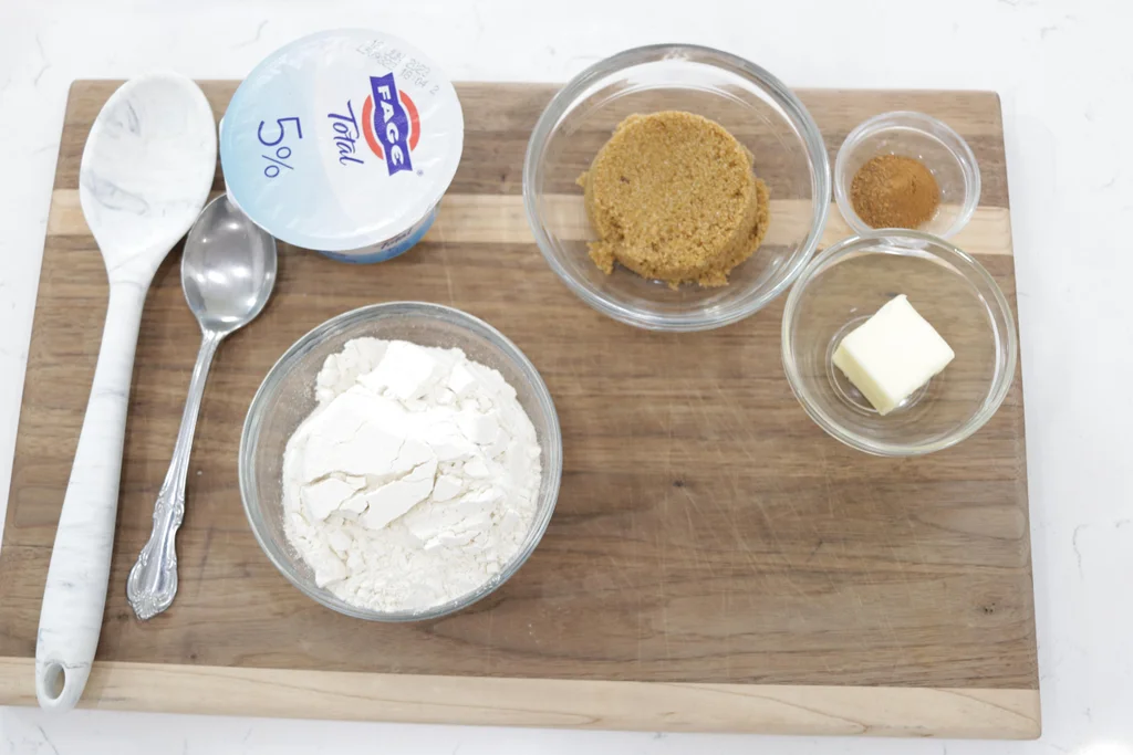 Flour, yogurt, brown sugar, butter, and cinnamon on a cutting board.