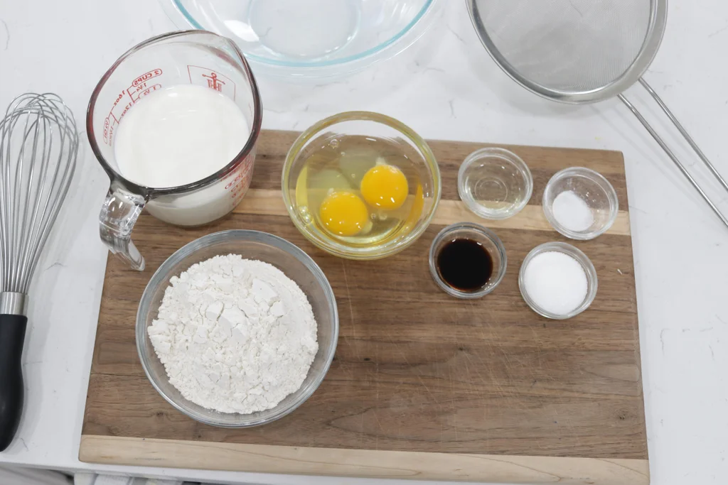 Gluten free flour and other ingredients in glass bowls on a cutting board.