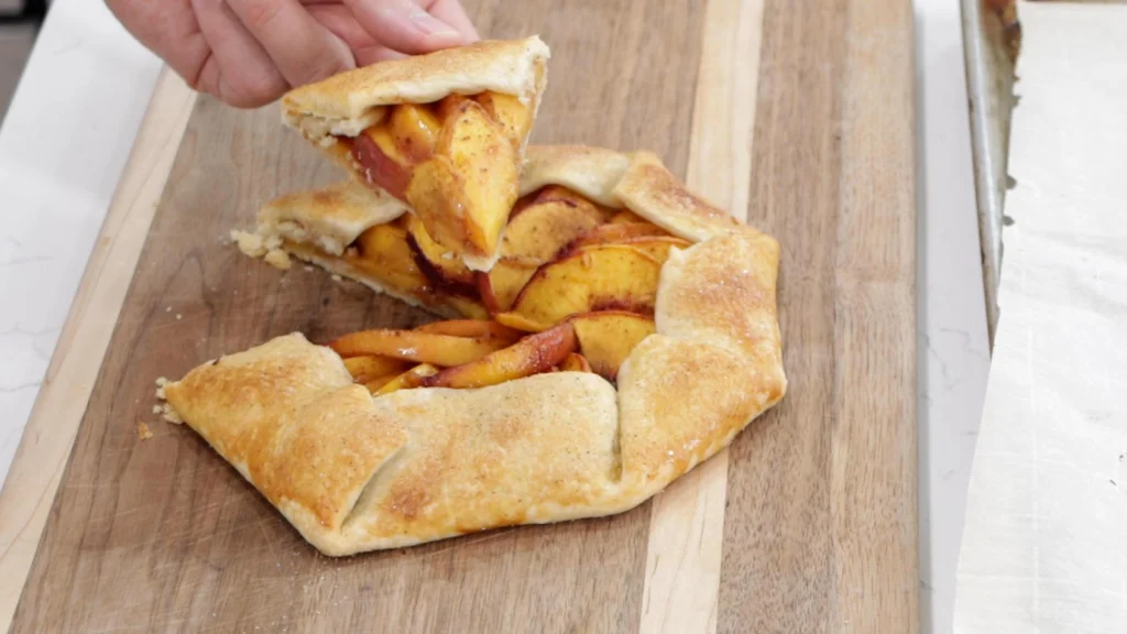 Hand holding a slice of a peach galette.