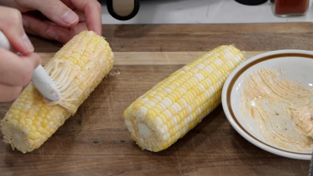 Basting the ears of corn with butter.