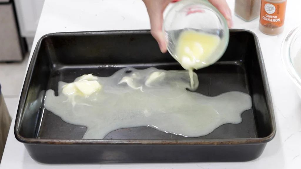 Melted butter being poured into a baking pan.