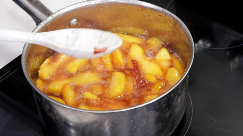 Peaches in a pot on a burner. 